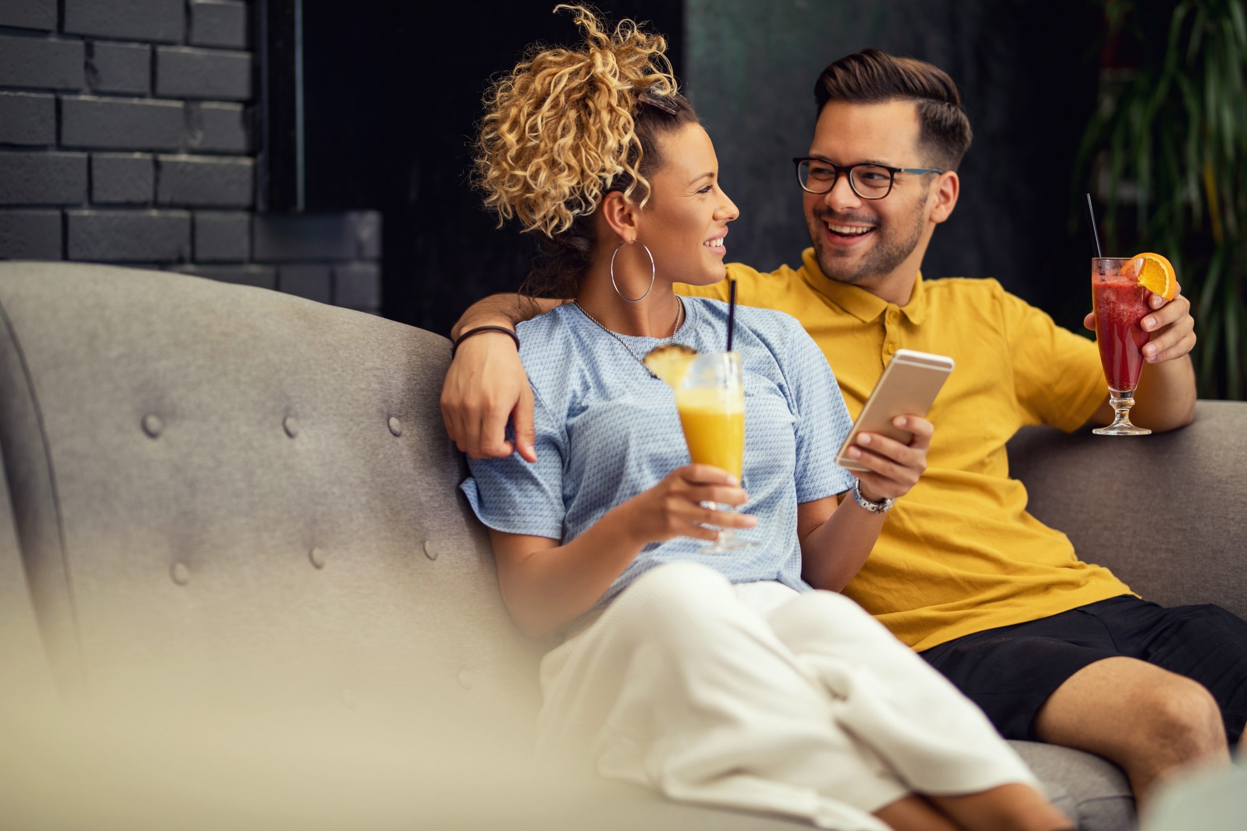 couple qui boit un cocktail dans le canapé à la maison