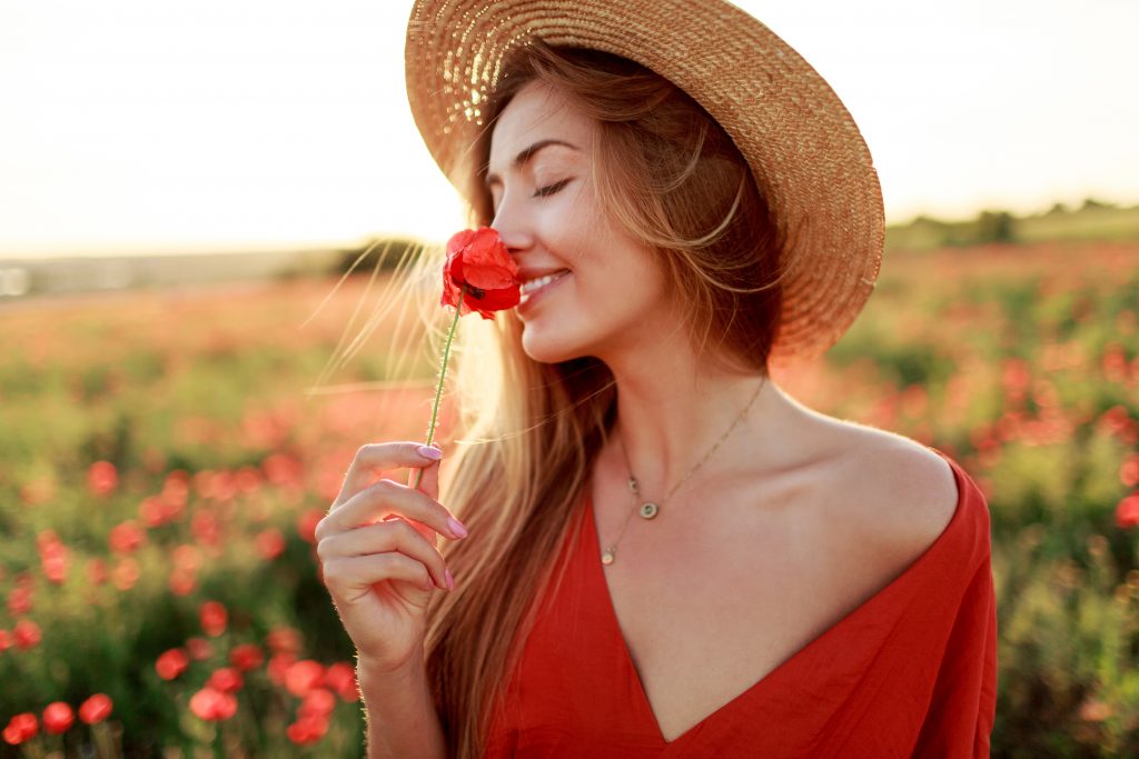romantique femme blonde avec des fleurs dans la main marchant dans un champ