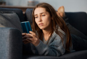 Fille triste sur son téléphone qui pense à son ex